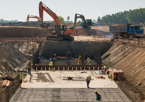 Close shot of heavy machines and construction workers working on a building